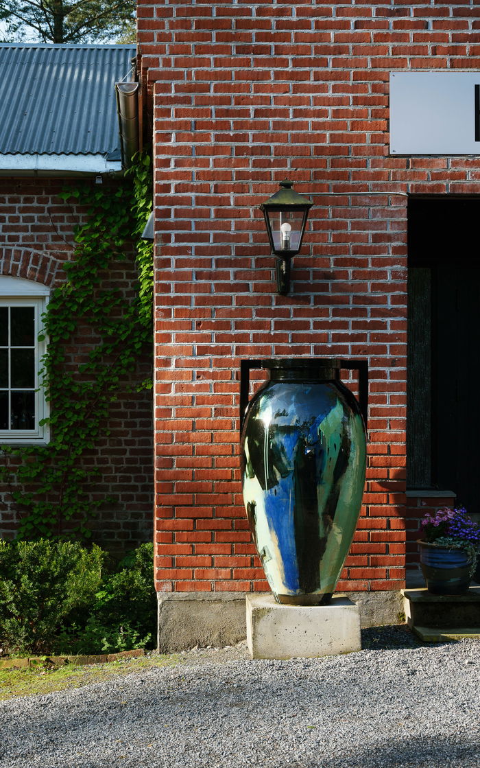 large scale jar in front of an old brick house